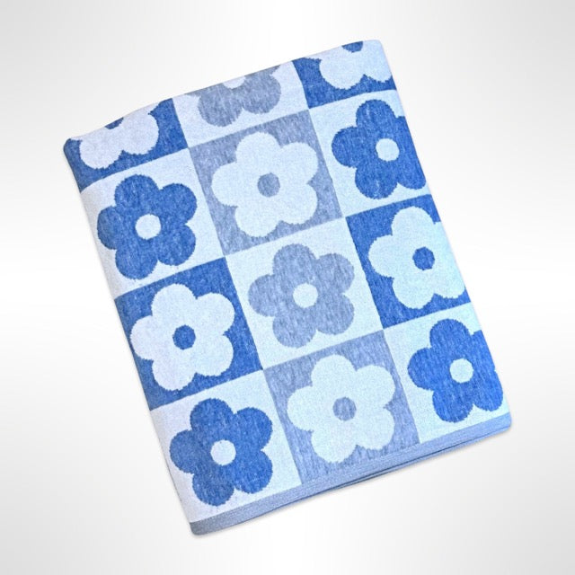 Large personalised beach towel with a simple flower shape in a repeating pattern in alternating shades of blue and grey.