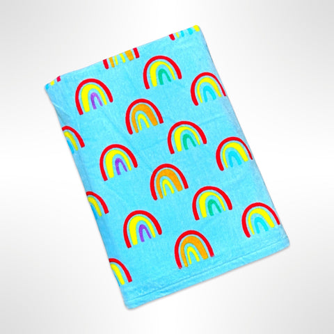 Large personalised beach towel with bright coloured rainbows on a light blue background.