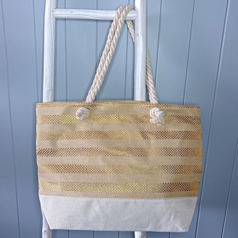 Personalised beach bag or beach tote bag hanging from a white timber ladder using its rope handle. The bag is natural colour with gold metallic stripes.