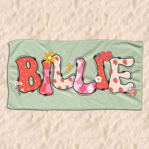 Light green childrens beach towel personalised with the name Billie in a groovy strawberry font