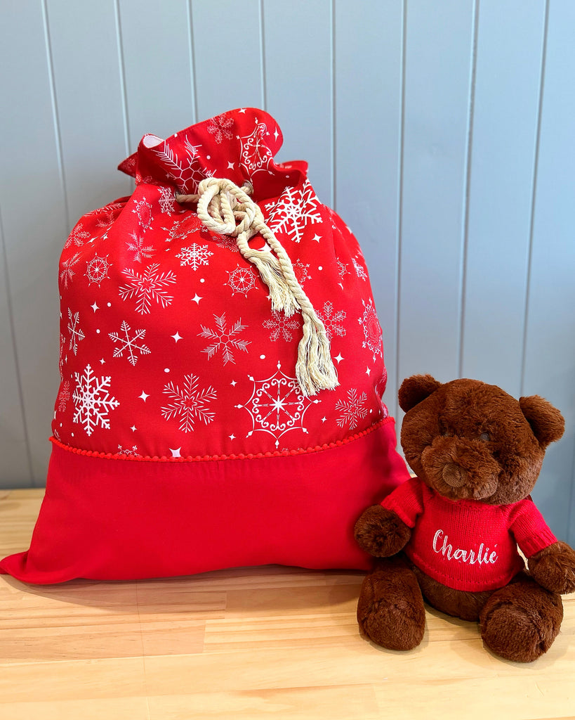 Large personalised Santa sack - main fabric is red with a white snowflake design. Bottom panel of plain red fabric. Rope cord drawstring.