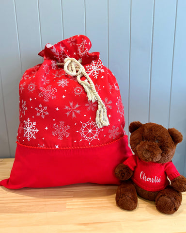 Large personalised Santa sack - main fabric is red with a white snowflake design. Bottom panel of plain red fabric. Rope cord drawstring.