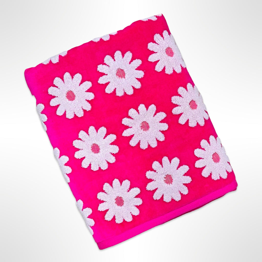 Personalised bath towel that has White daisy like flowers on a bright pink background.