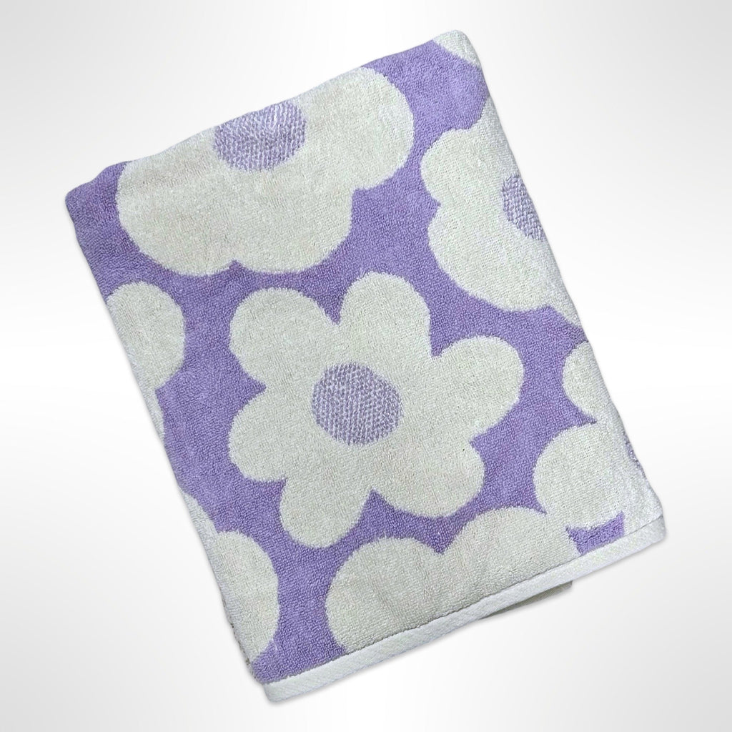 Personalised bath towel with large white flowers on a light purple background.