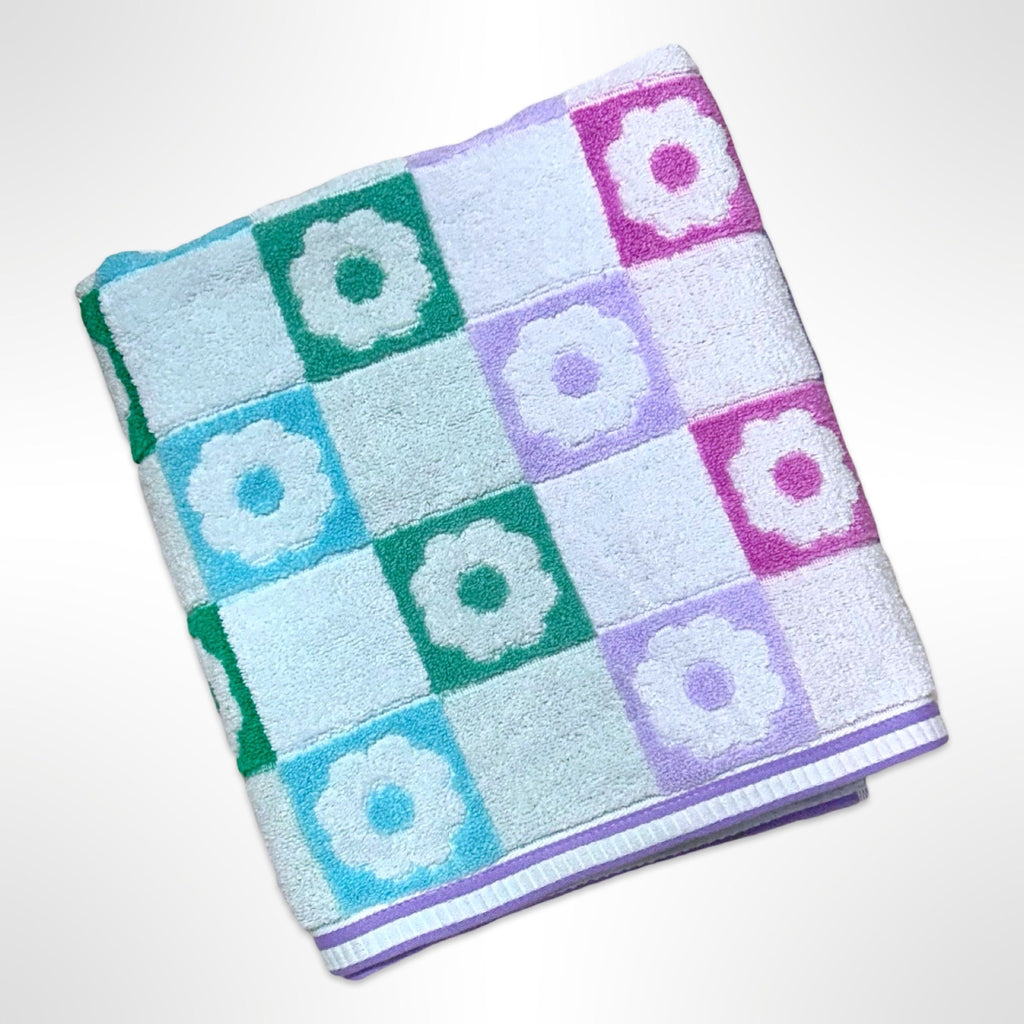 Personalised bath towel with flowers in pink, purple, green and blue.