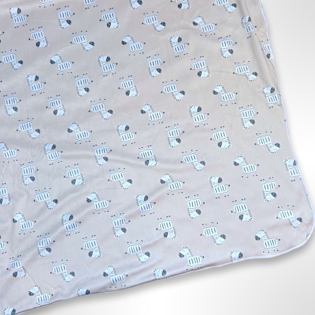 Double layer minky blanket with black and white zebras on a light brown background, ready to be personalised with a name using embroidery.