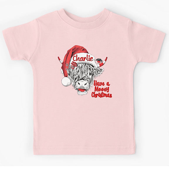 Pink short sleeved tshirt with face of black and white highland cow wearing a Christmas Santa Hat personalised with a name