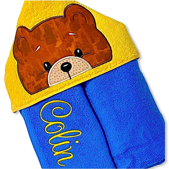 Hooded bath beach swim towel in blue with yellow hood. Hood has the face of a big brown bear appliquéd in the centre. Personalised with a name.