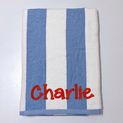 Beach towel in denim blue and white stripes, personalised with a name.