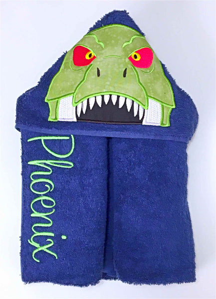 Blue bath beach swim towel with blue hood. Hood has a green dinosaur trex head appliquéd on it. Personalised with a name.