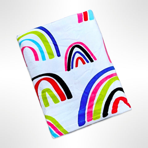 Large personalised beach towel with brightly coloured rainbows on a white background.