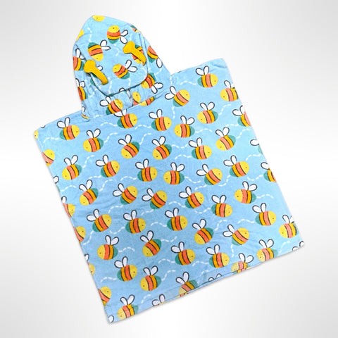 Junior sized beach poncho covered in bright yellow, orange and green striped bees on a light blue background, personalised with a name on the back.
