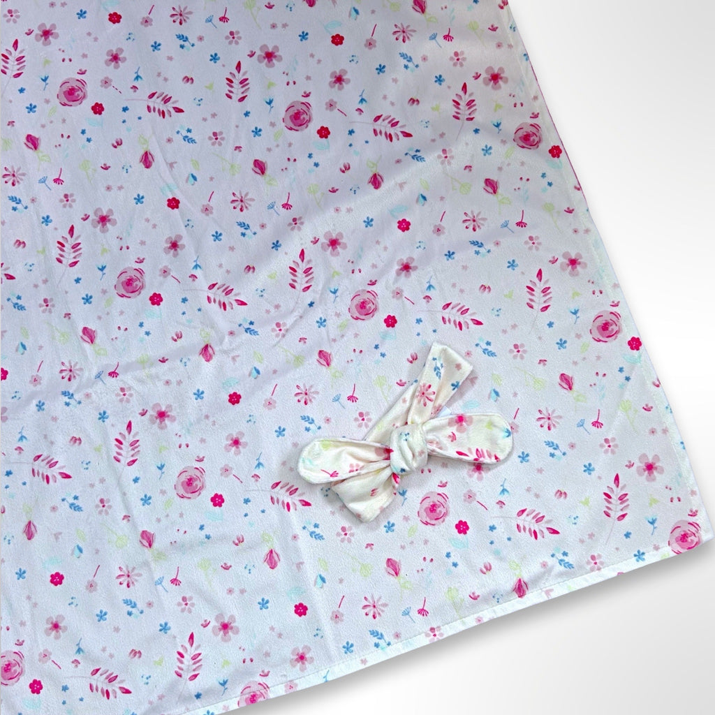 Double layer minky fleece blanket with dainty pink and blue flowers on a light pink background ready to be personalised with an embroidered name, along with matching knot headband