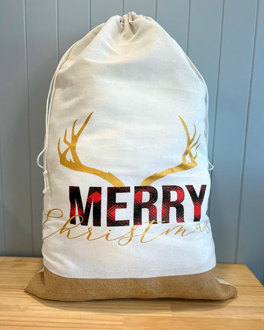 Extra large personalised Santa Sack with Merry written in a tartan pattern with Christmas written in gold underneath. Gold deer antlers sit above the words Merry Christmas.