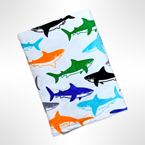 Large personalised beach towel with blue, orange, green and black sharks on a white background.