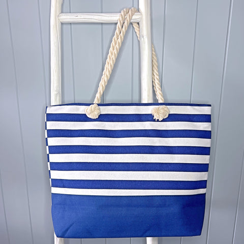 Personalised beach bag or beach tote bag hanging from a white timber ladder using its rope handles. The bag is navy and white stripes.