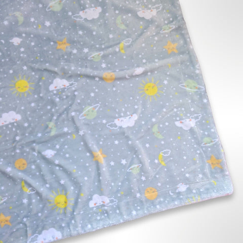 Minky blanket with a blue grey background covered in stars, planets, clouds and moons, ready to be personalised with a name using embroidery