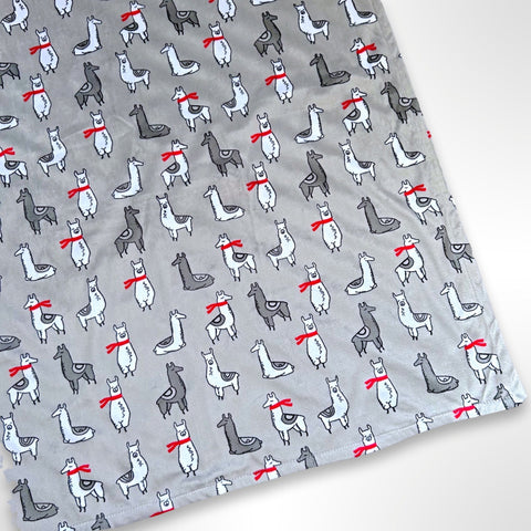 Double layer minky fleece blanket with grey and white llama wearing red scarves on a light grey background ready to be personalised with an embroidered name.