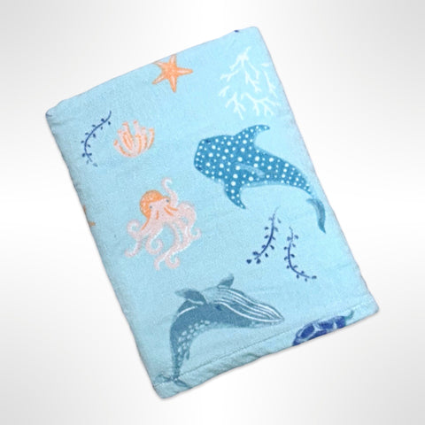 Children's personalised beach towel that has sharks, octopus and other sea creatures on a mint coloured background.