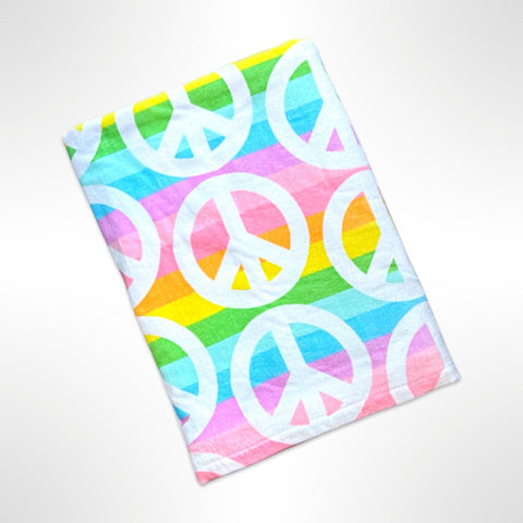 Personalised children's beach towel with white peace signs on a pastel rainbow coloured background.