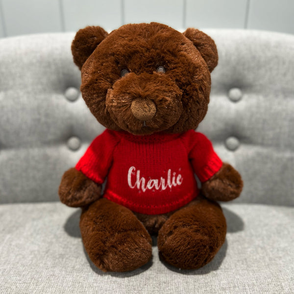 Dark brown maple bear softie wearing a bright red knitted jumper personalised with a name using white embroidery.