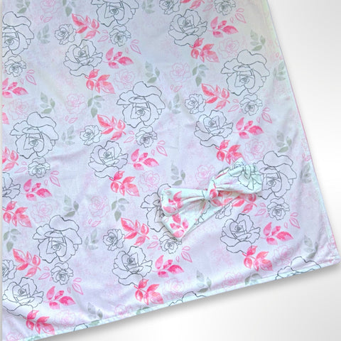 Double layer minky fleece blanket with pink and grey flowers on a light pink background ready to be personalised with an embroidered name, along with matching knot headband