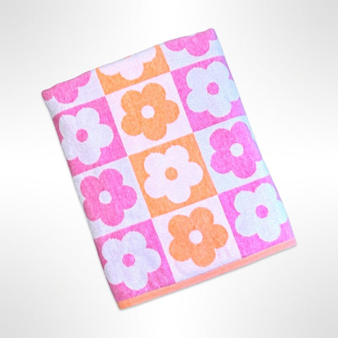 Large personalised beach towel with a simple flower shape in a repeating pattern in alternating shades of pink and orange.