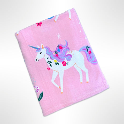 Childrens personalised beach towel that has colourful unicorns on a pastel pink background.
