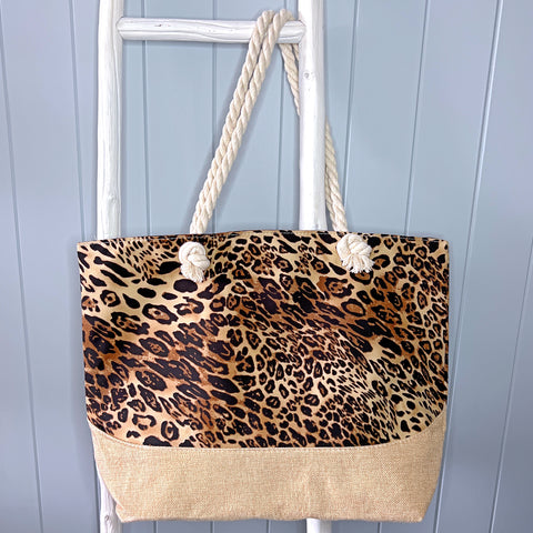 Large personalised beach bag or beach tote bag hanging from a white timber ladder from its rope handles. The bag is a sophisticated brown animal print design.