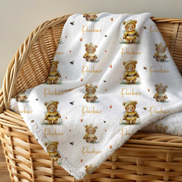Personalised minky blanket lying across a cane moses basket. The minky blanket has tan coloured bears dressed up as bees and the name Parker personalising the blanket.
