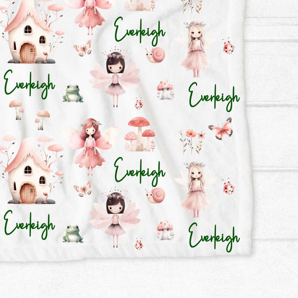 A close up of the corner of a personalised minky blanket. The blanket has fairies, toadstools, snails, butterflies, frogs and more all in pink shades.