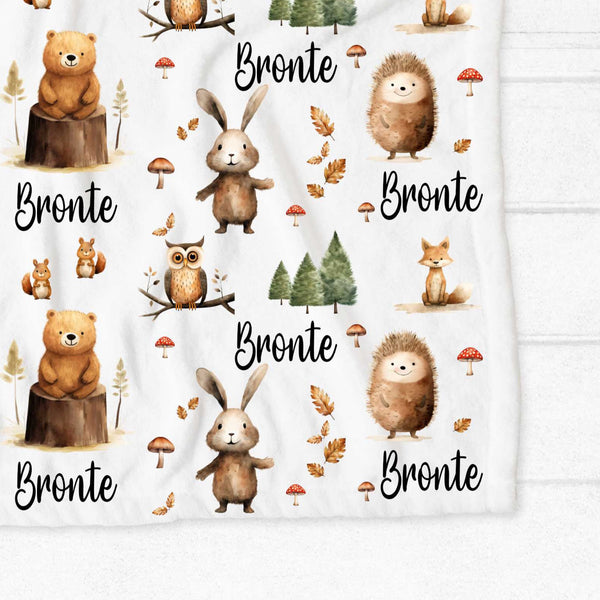 A close up of the corner of a personalised minky blanket. The blanket has woodland creatures including bears, chipmunks, owls, bunnies, foxes and hedgehogs.
