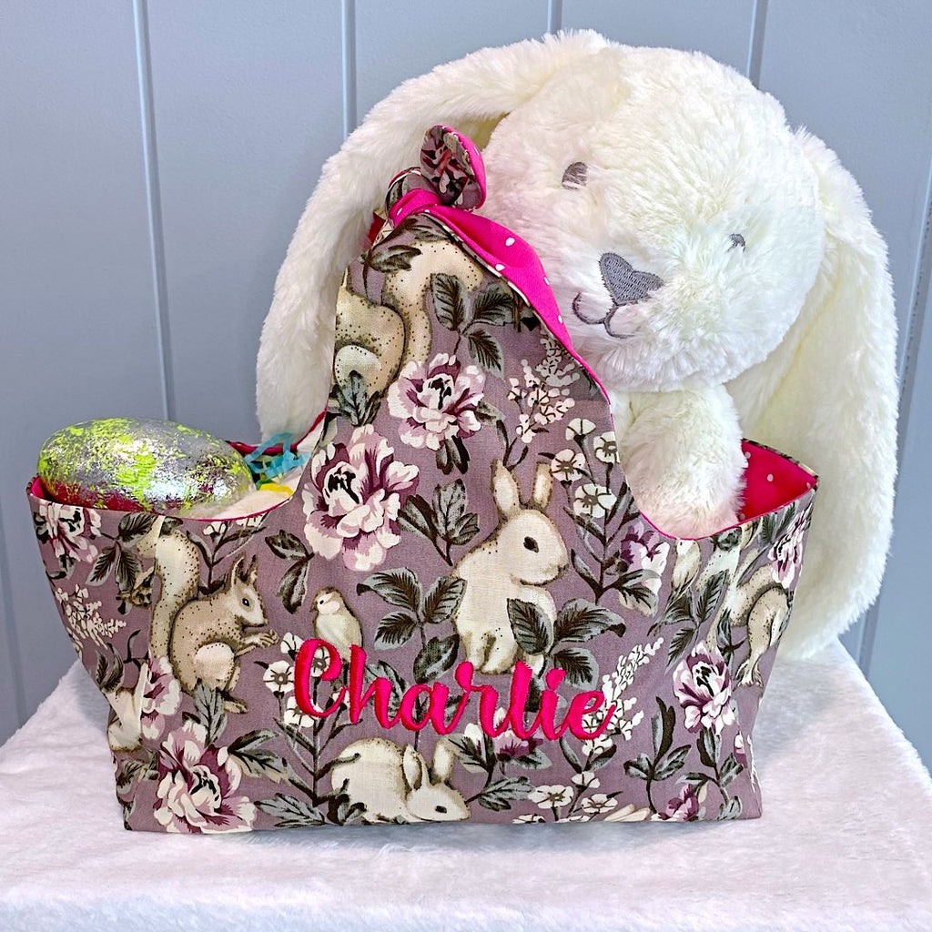 Handmade personalised easter basket bag with outer layer made out of a fabric with bunnies, squirrels, owls and roses on a dusty rose background and inner lining in a bright pink and white spot fabric