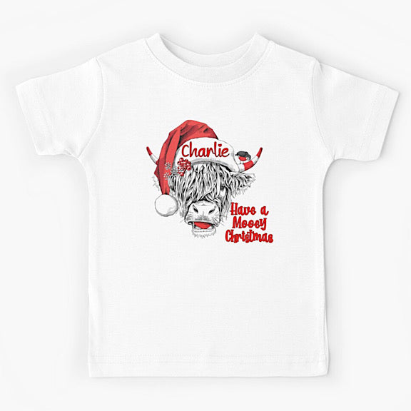 White short sleeved tshirt with face of black and white highland cow wearing a Christmas Santa Hat personalised with a name