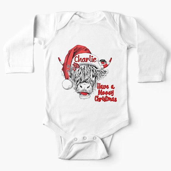White long sleeved baby onesie bodysuit with face of black and white highland cow wearing a Christmas Santa Hat personalised with a name
