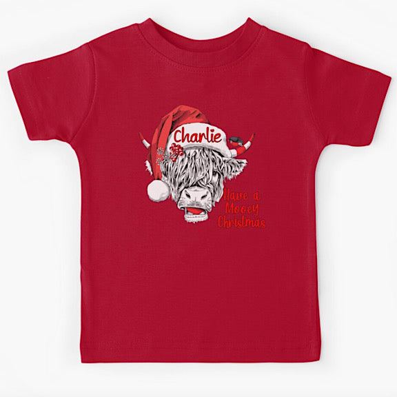 Red short sleeved tshirt with face of black and white highland cow wearing a Christmas Santa Hat personalised with a name