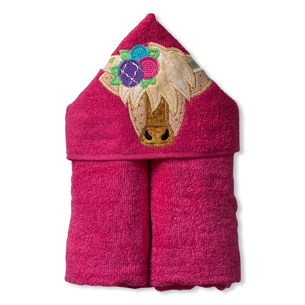 Hooded bath beach swim towel in pink with pink hood. Hood has the head of a highland Scottish cow in shades of brown and gold with flowers in the hair. Ready to be personalised.