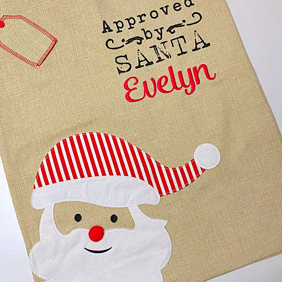 Burlap Christmas Santa Sack with appliqué of Santa's face in bottom left corner, personalised with a name