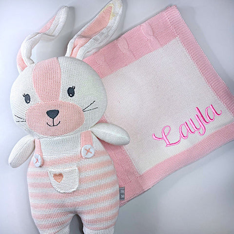 Pink and white knit blanket in a patchwork patten with a pink and white knitted first easter bunny with the blanket personalised with a light pink name