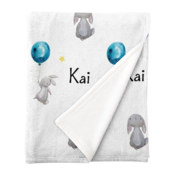 Personalised easter bunny fleece minky blanket with a white bunny tiptoeing holding onto a blue balloon and a white bunny looking up at the yellow stars