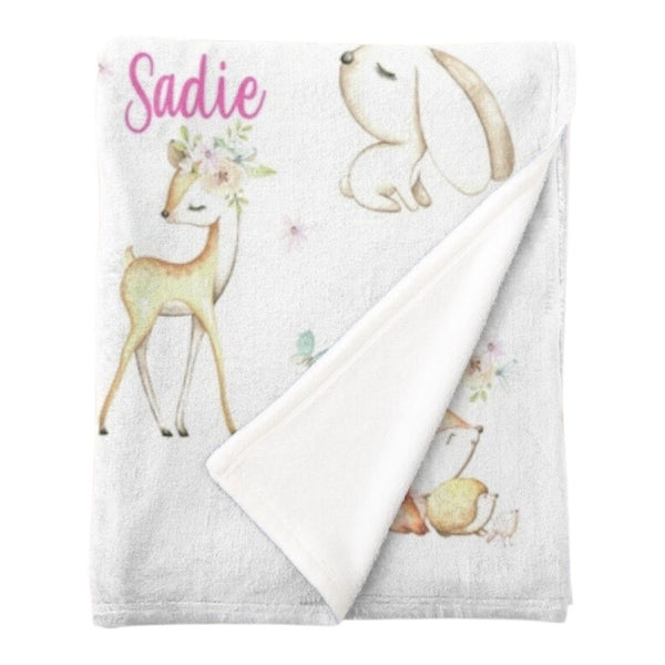 Personalised fleece minky blanket with the forest animals bunny, deer, squirrel, hedgehog and bird among a field of flowers and butterflies