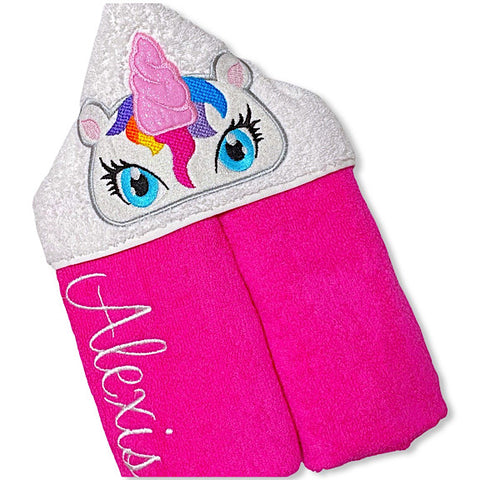 Hooded bath beach swim towel in pink with white hood. Hood has the face of glittery white unicorn with large eyes appliquéd in the centre. Personalised with a name.