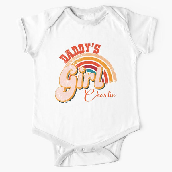 Short sleeved white baby onesie with Daddy's Girl written in retro 70s style writing over the top of a rainbow. The colours are a mix of reds, oranges and yellows. The onesie has been personalised with the daughter's name.