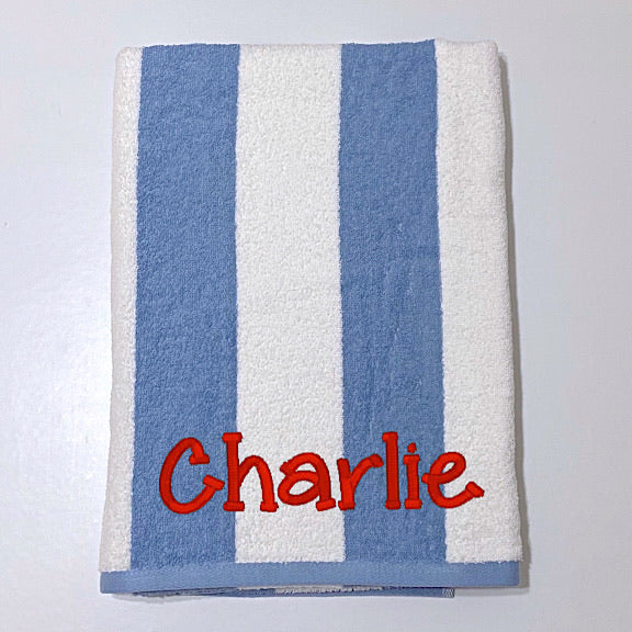 Beach towel in denim blue and white stripes, personalised with a name.