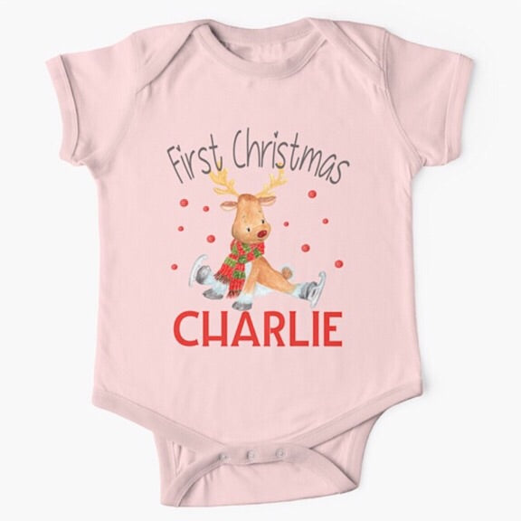 Personalised light pink short sleeved baby onesie bodysuit for first Christmas with a reindeer wearing a red and green scarf trying to ice skate