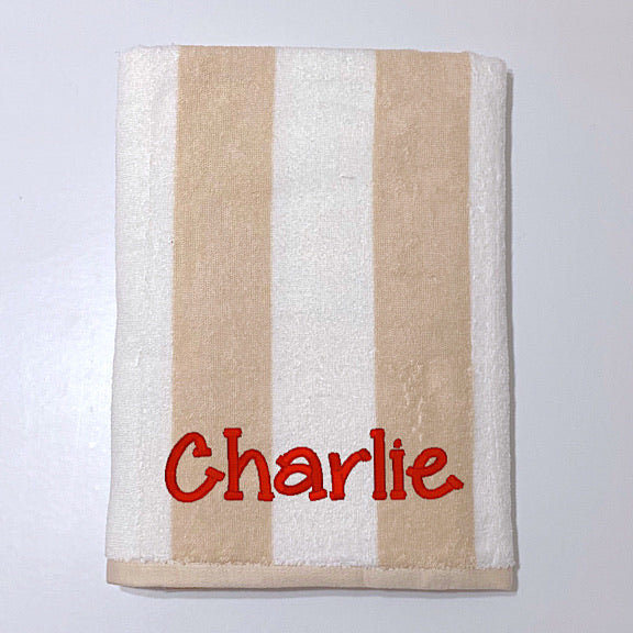 Beach towel in beige cream and white stripes, personalised with a name.