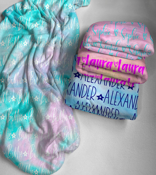 Four different personalised tie dye minky fleece blankets stacked onto a plasterboard background