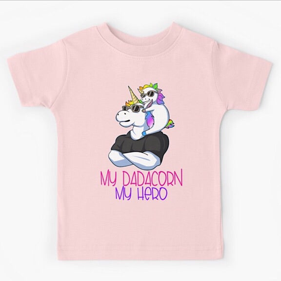Light pink short sleeved kids tshirt with a muscly white father unicorn wearing a black tshirt with a baby unicorn on his shoulders with the words my dadacorn my hero underneath