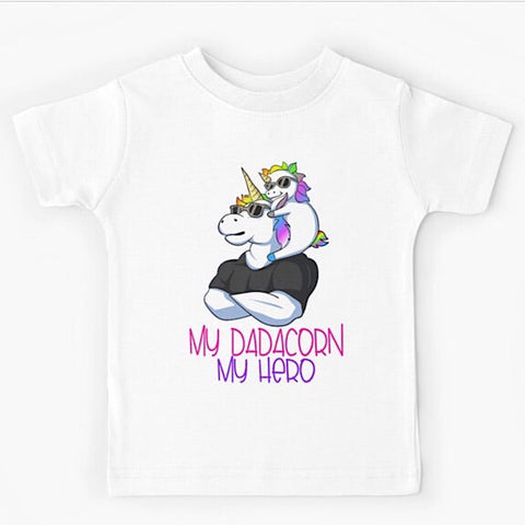 White short sleeved kids tshirt with a muscly white father unicorn wearing a black tshirt with a baby unicorn on his shoulders with the words my dadacorn my hero underneath