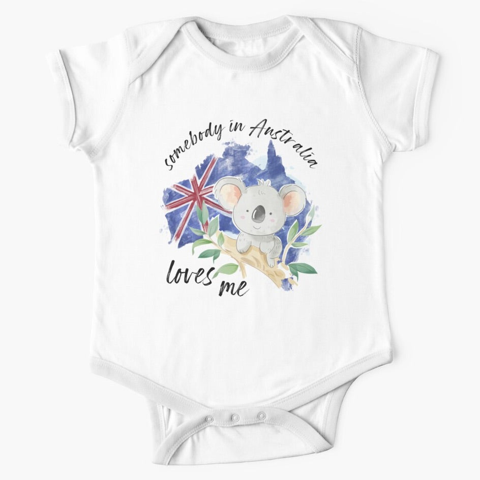 White short sleeved onesie with somebody in Australia loves you written in cursive text around the picture of a grey koala sitting on the branch of a gumtree on the background of the australian flag